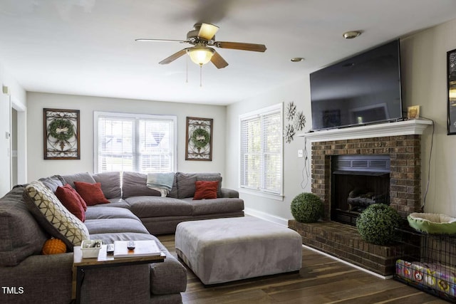 living room with ceiling fan, dark hardwood / wood-style flooring, a healthy amount of sunlight, and a brick fireplace