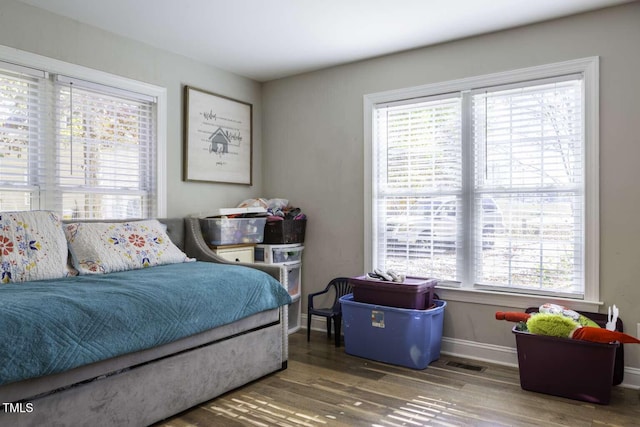 bedroom featuring multiple windows and dark hardwood / wood-style flooring