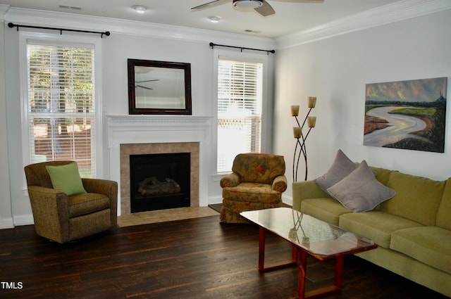 living area featuring a ceiling fan, wood finished floors, visible vents, ornamental molding, and a tiled fireplace