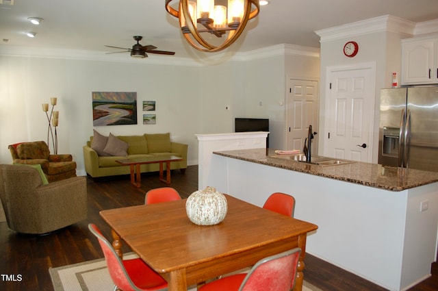 dining room featuring dark wood finished floors, ceiling fan with notable chandelier, and crown molding