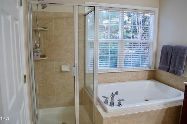 bathroom with a wealth of natural light, a garden tub, and a shower stall