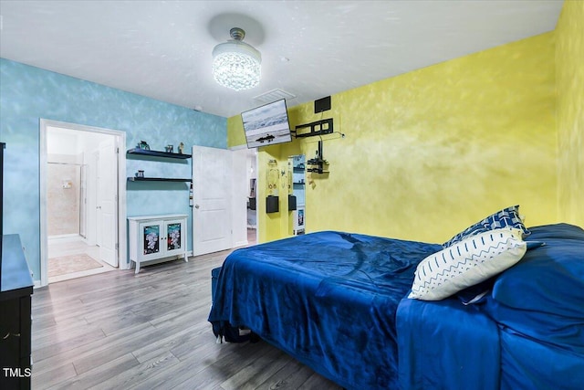 bedroom with hardwood / wood-style floors and ensuite bathroom