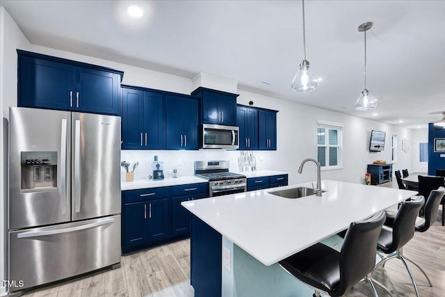 kitchen featuring sink, light wood-type flooring, an island with sink, a kitchen bar, and stainless steel appliances