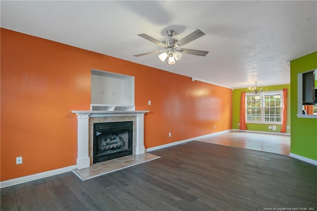 unfurnished living room featuring crown molding, a textured ceiling, a tiled fireplace, ceiling fan with notable chandelier, and hardwood / wood-style flooring