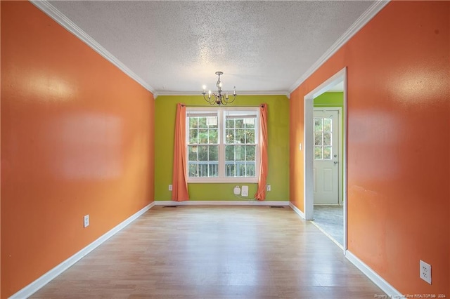 unfurnished dining area with a textured ceiling, an inviting chandelier, light hardwood / wood-style flooring, and crown molding