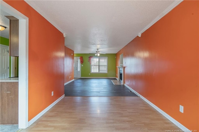 hallway featuring crown molding, a textured ceiling, and light wood-type flooring