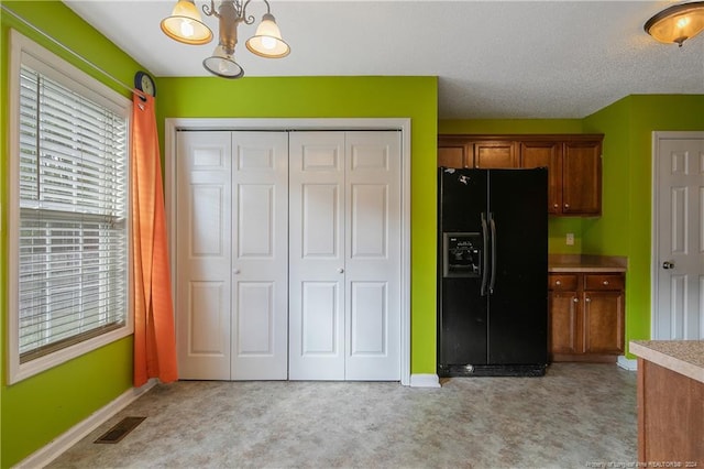 kitchen featuring hanging light fixtures, an inviting chandelier, black refrigerator with ice dispenser, a textured ceiling, and light carpet