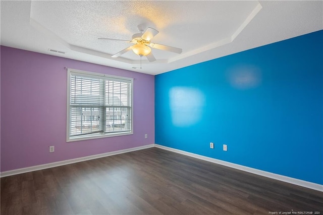 spare room featuring ceiling fan, a tray ceiling, dark hardwood / wood-style floors, and a textured ceiling