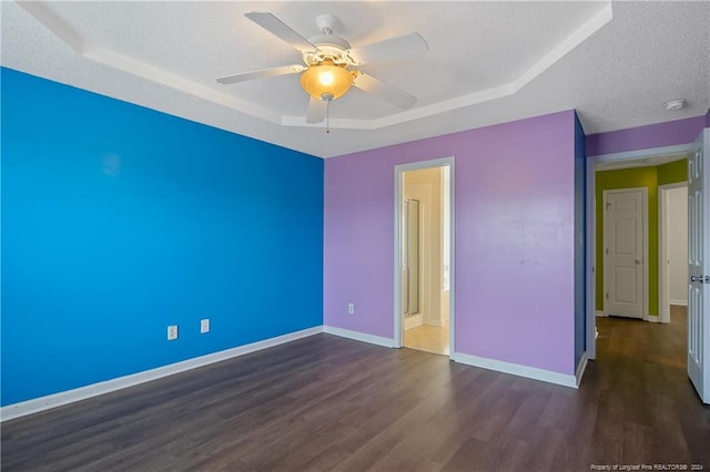 unfurnished room featuring ceiling fan, a raised ceiling, dark hardwood / wood-style floors, and a textured ceiling