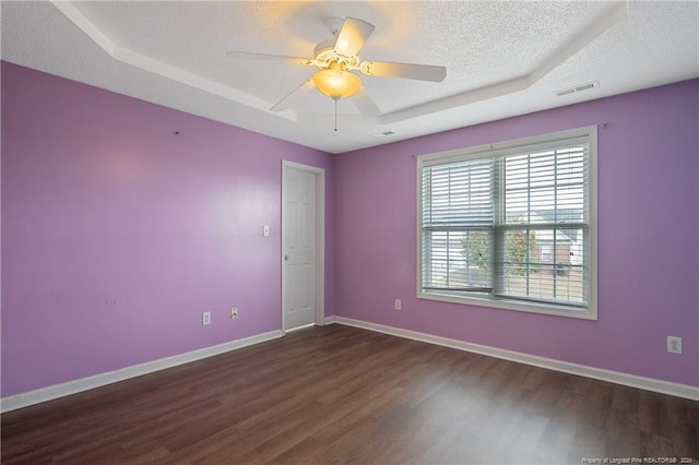 unfurnished room with ceiling fan, dark wood-type flooring, a tray ceiling, and a textured ceiling