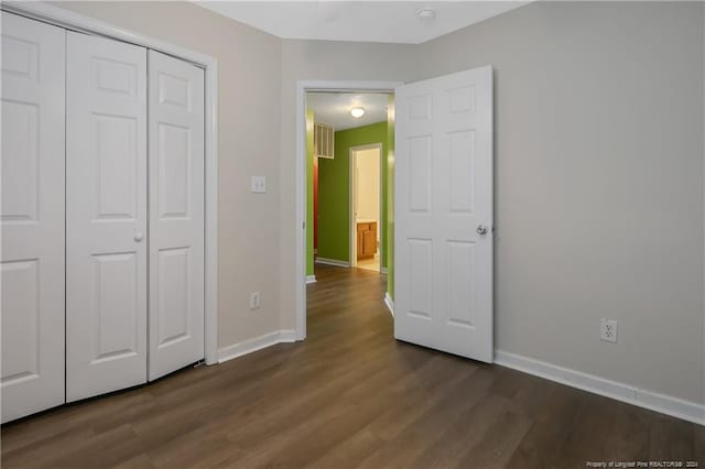 unfurnished bedroom with a closet and dark hardwood / wood-style flooring