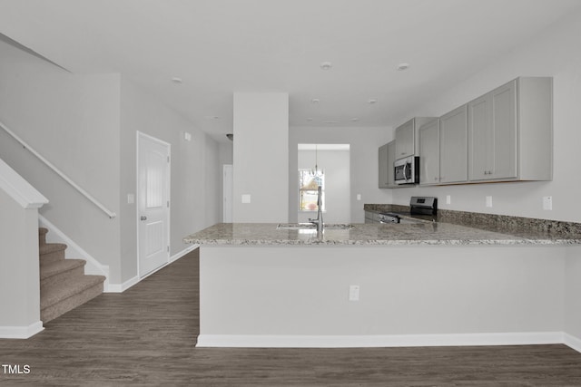 kitchen with sink, dark hardwood / wood-style floors, kitchen peninsula, gray cabinets, and appliances with stainless steel finishes