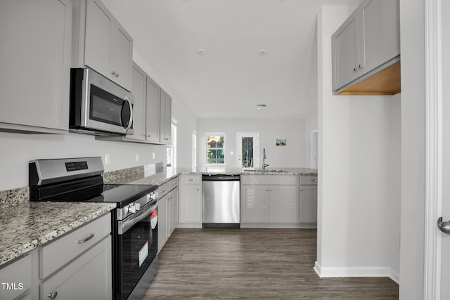 kitchen with light stone counters, sink, stainless steel appliances, and dark hardwood / wood-style floors