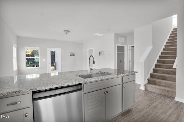 kitchen with light stone countertops, gray cabinetry, sink, light hardwood / wood-style flooring, and dishwasher