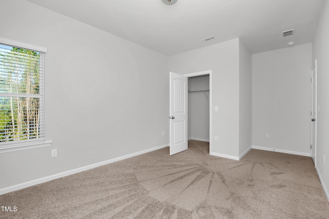 unfurnished bedroom with light colored carpet and a closet