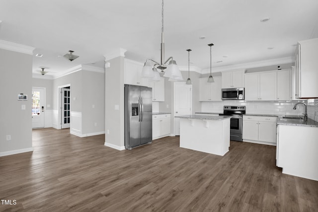 kitchen with stainless steel appliances, decorative light fixtures, white cabinets, a center island, and dark hardwood / wood-style floors