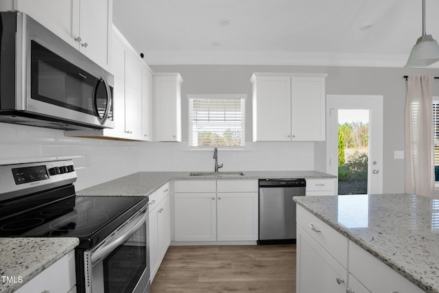 kitchen featuring appliances with stainless steel finishes, sink, light hardwood / wood-style flooring, white cabinetry, and hanging light fixtures