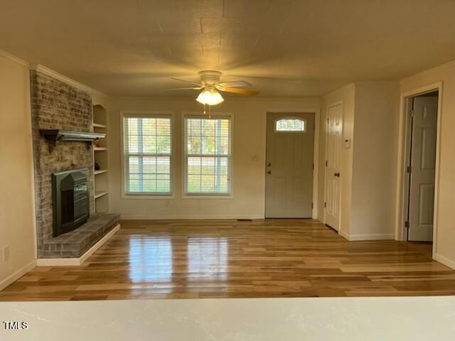 unfurnished living room featuring a brick fireplace, light hardwood / wood-style flooring, built in features, and ceiling fan