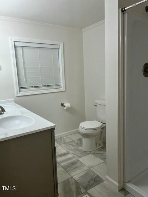 bathroom featuring a shower, crown molding, vanity, and toilet