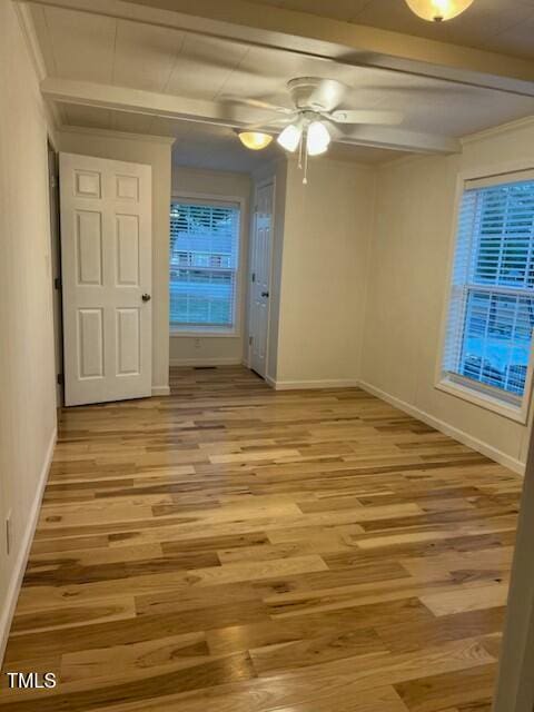 spare room featuring ceiling fan, beam ceiling, and light hardwood / wood-style flooring