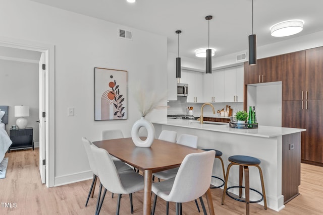 interior space featuring decorative light fixtures, light hardwood / wood-style floors, white cabinetry, and stainless steel appliances