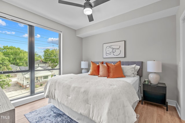 bedroom with multiple windows, ceiling fan, and light wood-type flooring