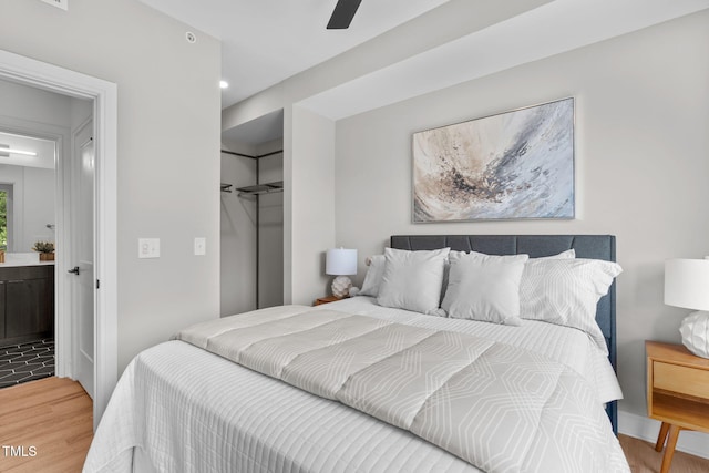 bedroom featuring hardwood / wood-style floors, ceiling fan, connected bathroom, and a closet