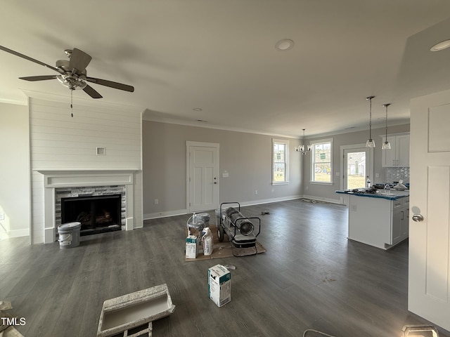 unfurnished living room with dark wood finished floors, a fireplace, crown molding, and baseboards