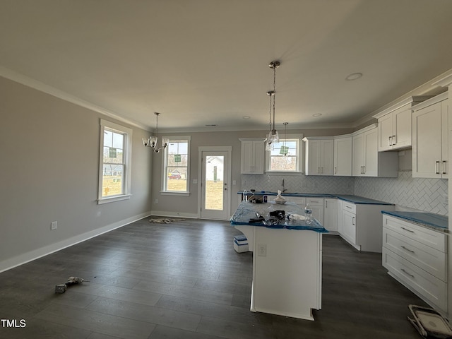 kitchen featuring backsplash, a kitchen island, dark wood finished floors, and crown molding