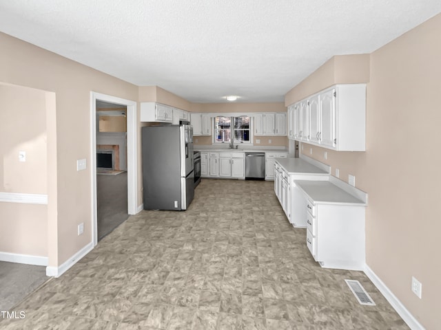 kitchen featuring white cabinets, appliances with stainless steel finishes, a textured ceiling, and sink