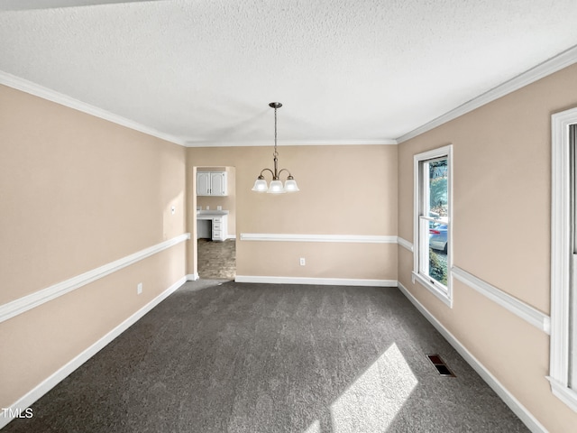 unfurnished dining area with dark colored carpet, a notable chandelier, crown molding, and a textured ceiling