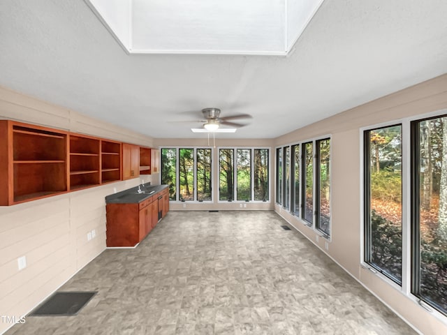 unfurnished sunroom with a skylight, ceiling fan, and sink