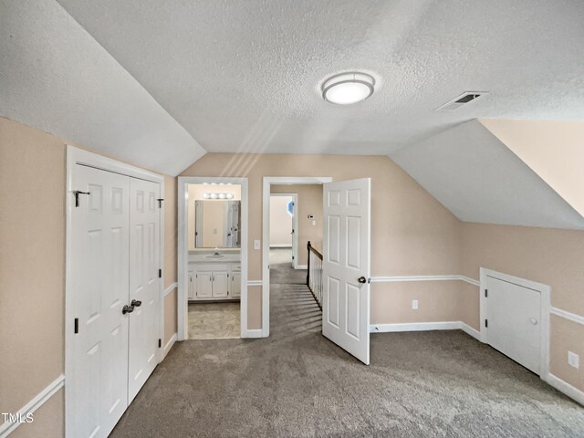 bonus room featuring a textured ceiling, carpet floors, and lofted ceiling