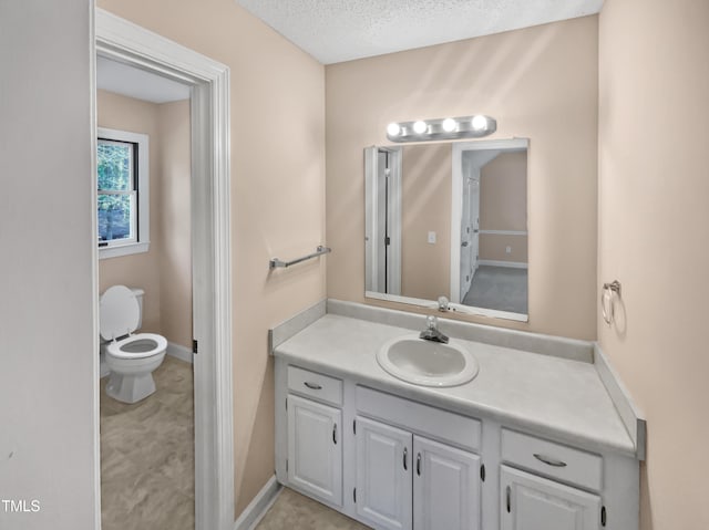 bathroom featuring vanity, a textured ceiling, and toilet