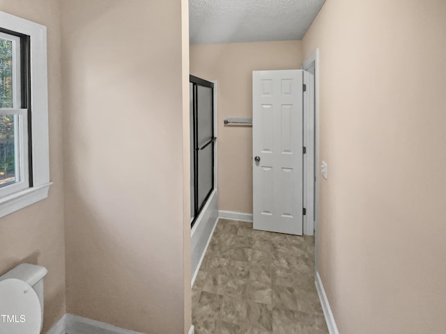 interior space with walk in shower, a textured ceiling, and toilet