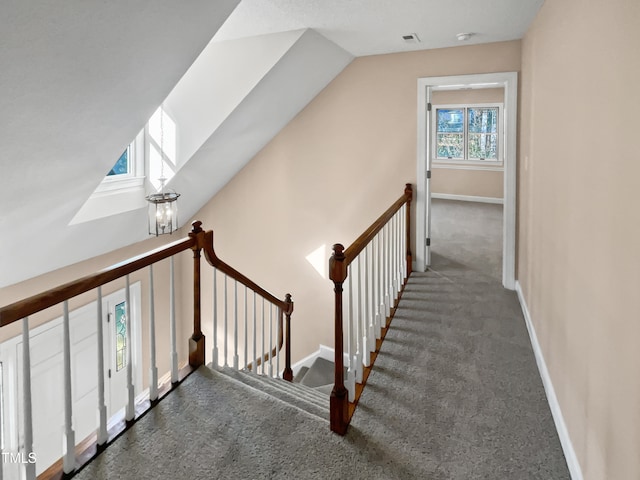 staircase with a chandelier, carpet floors, and lofted ceiling