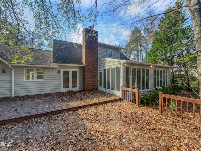 back of property with a sunroom, a deck, and french doors