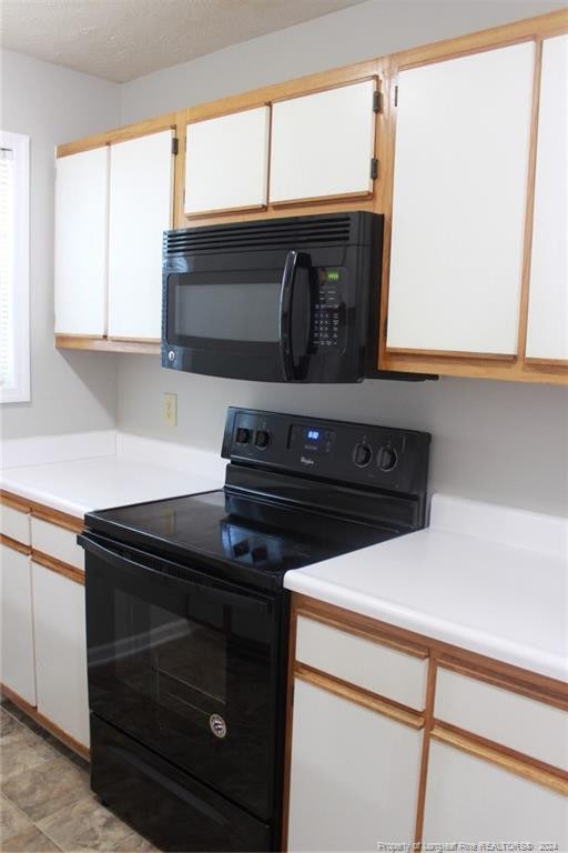 kitchen featuring white cabinets, a textured ceiling, and black appliances