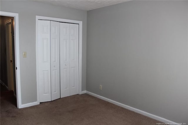 unfurnished bedroom featuring a closet, dark colored carpet, and a textured ceiling