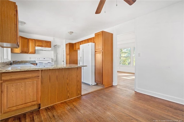 kitchen featuring ceiling fan, light stone counters, kitchen peninsula, light hardwood / wood-style floors, and white appliances