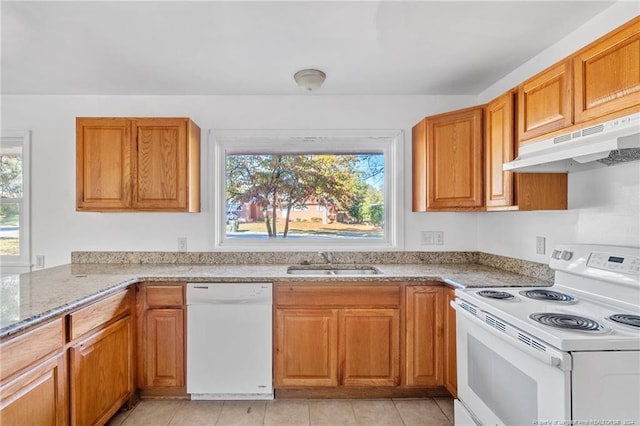 kitchen featuring white appliances, sink, light tile patterned flooring, and light stone counters