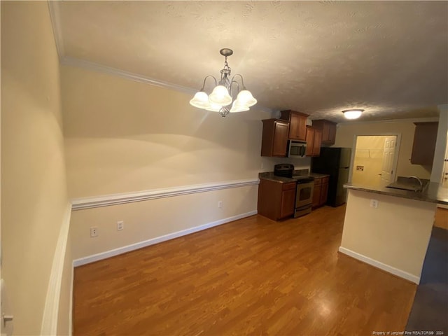 kitchen featuring hardwood / wood-style floors, pendant lighting, crown molding, and stainless steel appliances