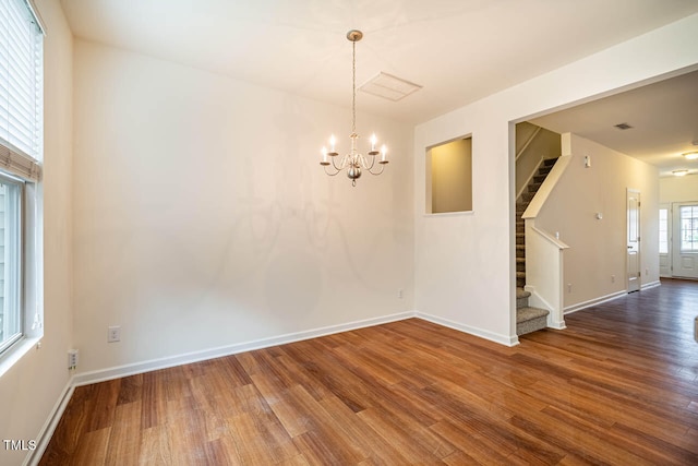 spare room featuring hardwood / wood-style floors and a notable chandelier