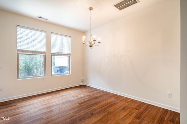 unfurnished room featuring wood-type flooring and a notable chandelier