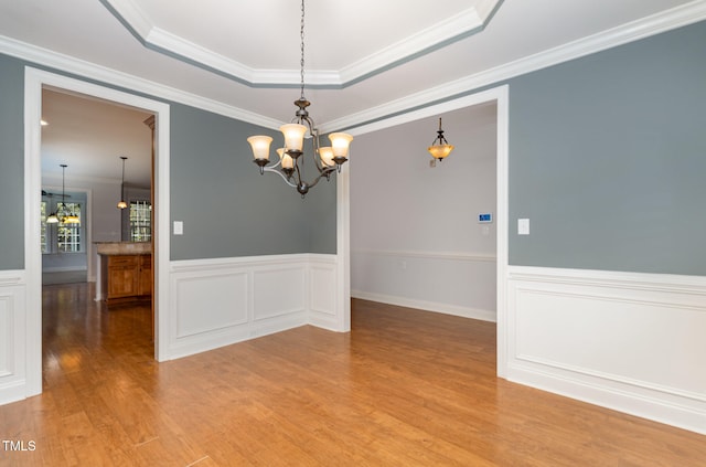 unfurnished room with a notable chandelier, wood-type flooring, and ornamental molding