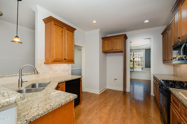 kitchen with light stone counters, sink, black appliances, light hardwood / wood-style floors, and hanging light fixtures