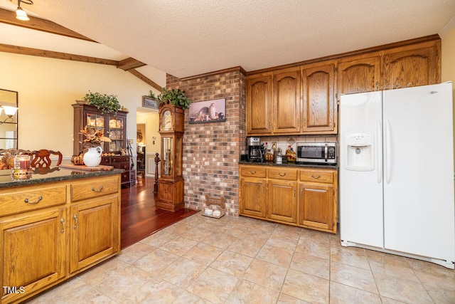 kitchen with lofted ceiling with beams, light wood-type flooring, white fridge with ice dispenser, a textured ceiling, and brick wall