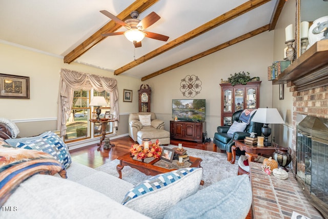 living room featuring ceiling fan, lofted ceiling with beams, hardwood / wood-style flooring, and a brick fireplace