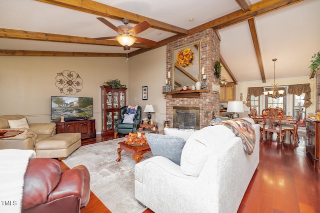 living room featuring ceiling fan with notable chandelier, dark hardwood / wood-style flooring, lofted ceiling with beams, and a brick fireplace