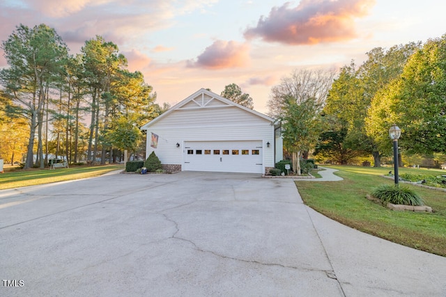 property exterior at dusk with a garage and a yard